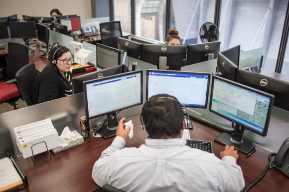 A bank of screens helps operators navigate city systems for residents calling for help.