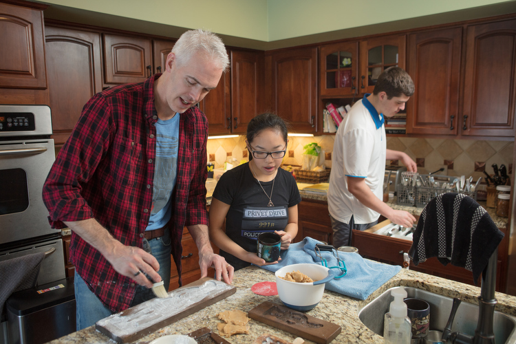 A transracial family, Bill Boersma, left, bakes cookies with kids Liana, middle, and Curran, right.
