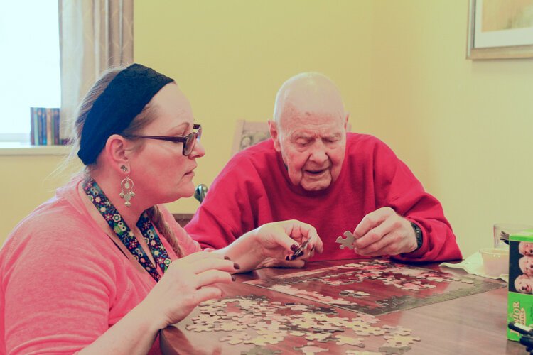 Sandy Loveless, a certified nurses aide, (left) and William Schavey work on a puzzle together at the LifeCircles PACE Hub in Holland Township on a recent afternoon.