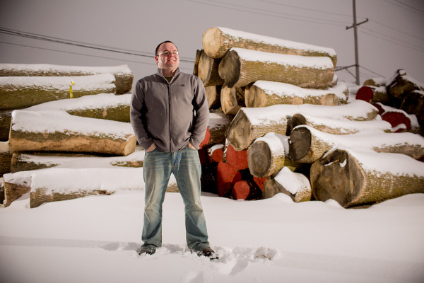 KC Weaver stands in front of stacks of curing elm wood.