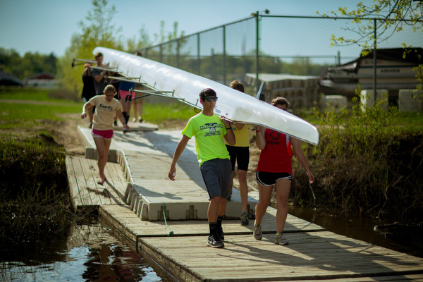 Students bring a shell to the Grand River to practice rowing.