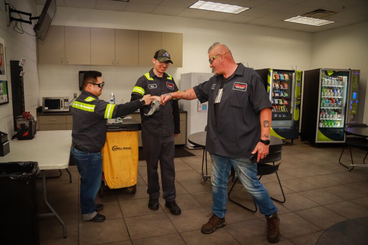 Will Dirk Bakhuyzen fist-bumps his co-workers.Nick and CJ at Weller Truck Parts. 