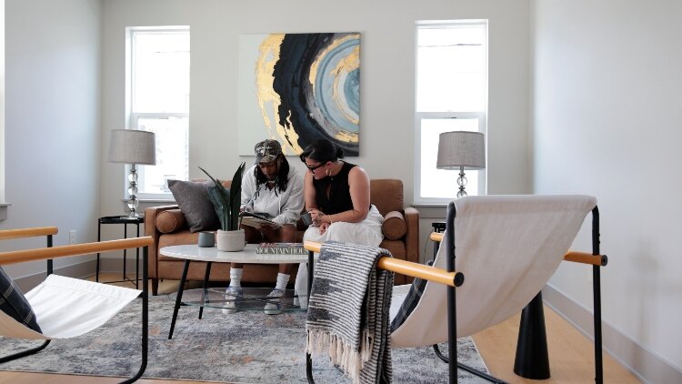 A couple sits in the living room of a staged CLT home at 2080 Union, showing off the space.