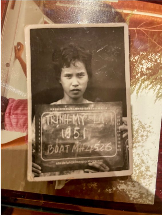Ethan Lien’s grandmother holds a sign displaying her boat number, commemorating her journey as part of the Vietnamese boat people in 1951.