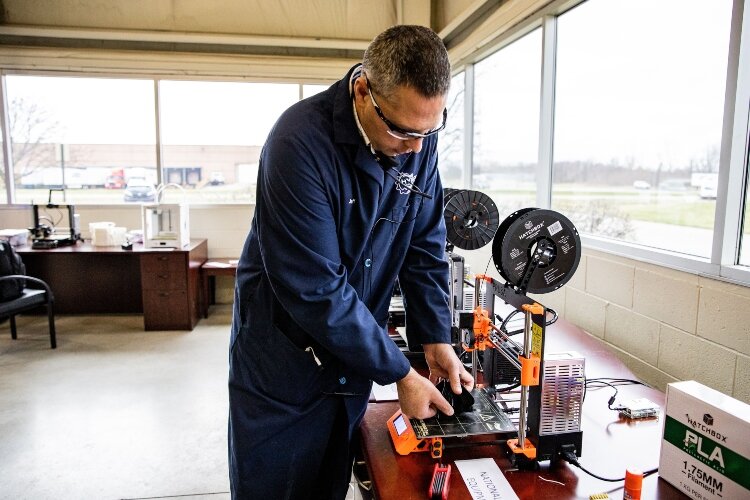 Jeff Robinson of Hybrid Machining removes a 3D printed face mask from a printer donated by Reed City at Hybrid Machining.