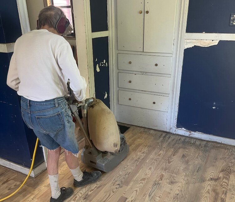 Carol Moore, local preservationist and founder of Hermitage at Diamond, sands the floor of the historic building.