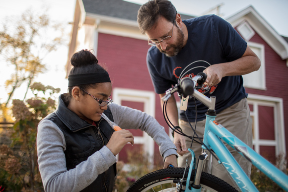 Lilyana Coleman, left, gets help from Jeff Hutchinson, right, adjusting her brakes. 