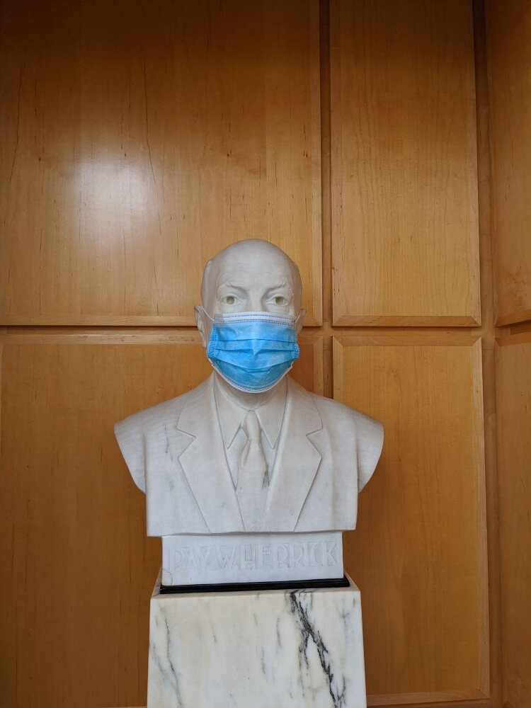 A statute of Ray Herrick is masked, signaling that everyone has to wear a mask at Herrick District Library.