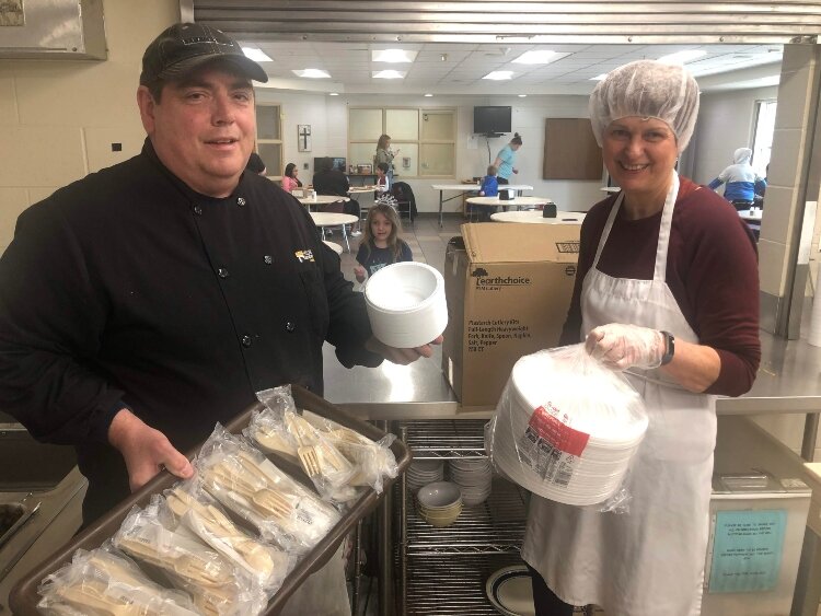 Holland Rescue Mission Food Services Director Frank Wilson (left) and a volunteer display donated utensils and plates to be used in the Mission's food centers.