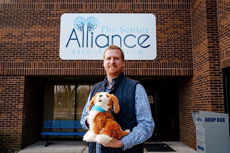 Andrew Dabrowski, community care program manager for The Senior Alliance, holds a Joy for All robotic dog.