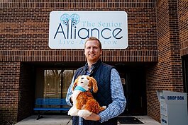 Andrew Dabrowski, community care program manager for The Senior Alliance, holds a Joy for All robotic dog.