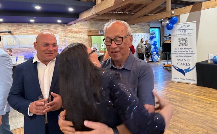 Raquel Guzman hugs her mentor, Bing Goei, with her husband, Rene Guzman, looking on. 