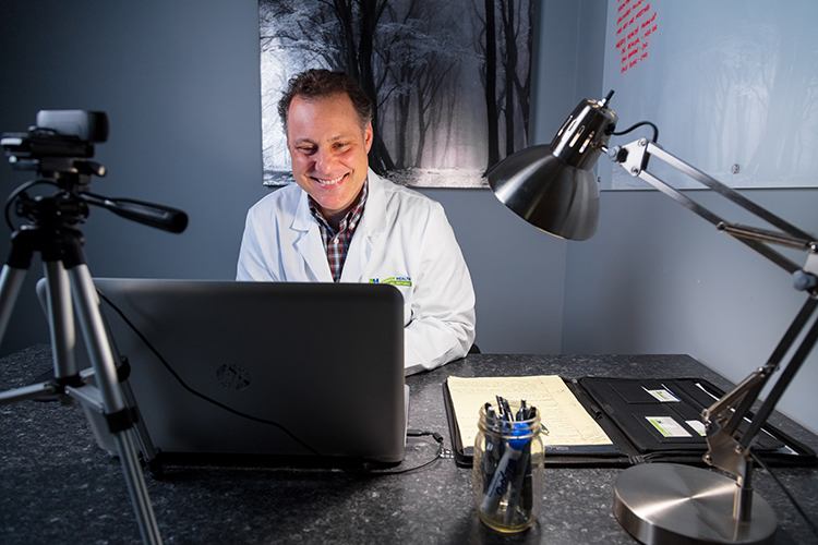  Dr. John Deveau speaks with patients over video chat. 