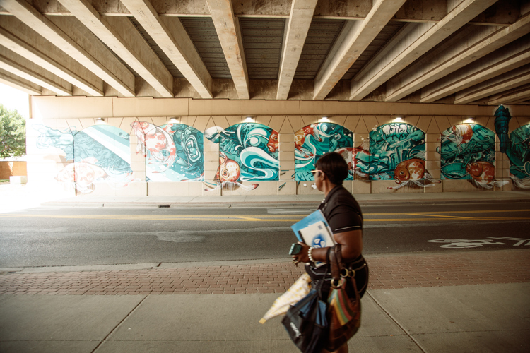 Pedestrians walk past the mural under US 131 on Front St. 