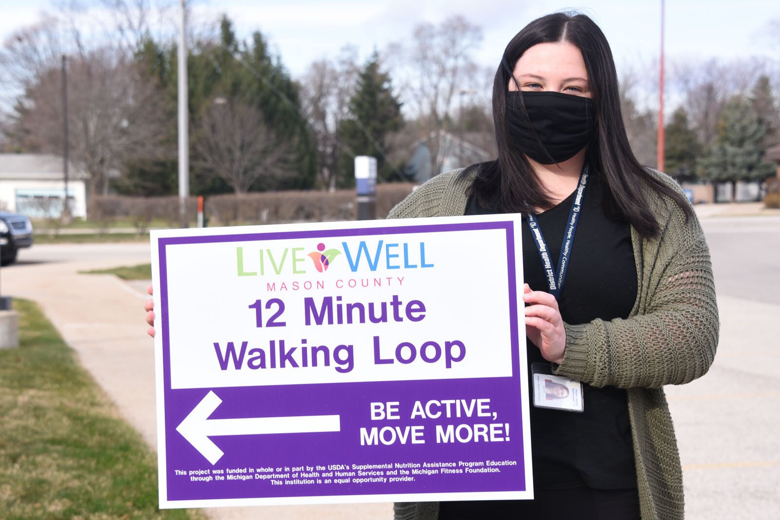 Erin Barrett holds a walking trail sign in Ludington.