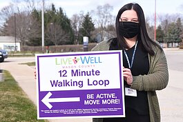 Erin Barrett holds a walking trail sign in Ludington.