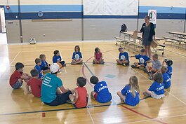 Campers at the YMCA summer day camp at Petoskey's Ottawa Elementary School play a game, hosted by Health Department of Northwest Michigan staff, in which they try to guess what fruit or vegetable is in a bag without looking.