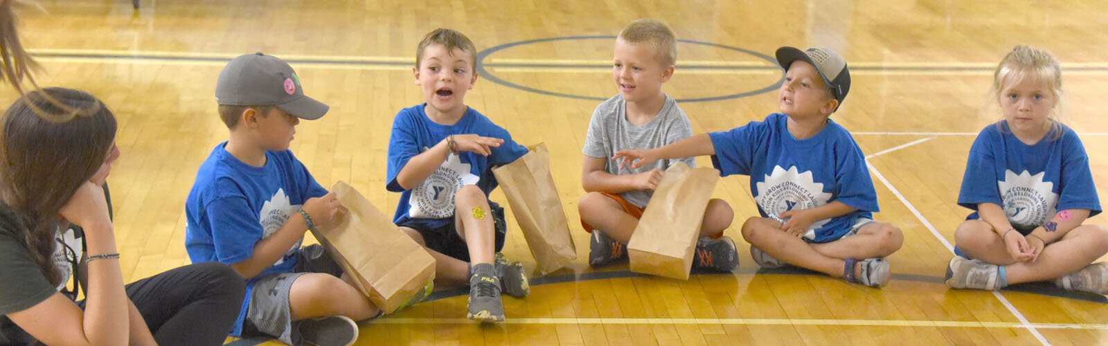 Campers at the YMCA summer day camp at Petoskey's Ottawa Elementary School play a game, hosted by Health Department of Northwest Michigan staff, in which they try to guess what fruit or vegetable is in a bag without looking.