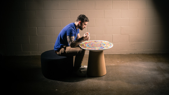 Chuck Anderson writes on the table he designed for Turnstone.