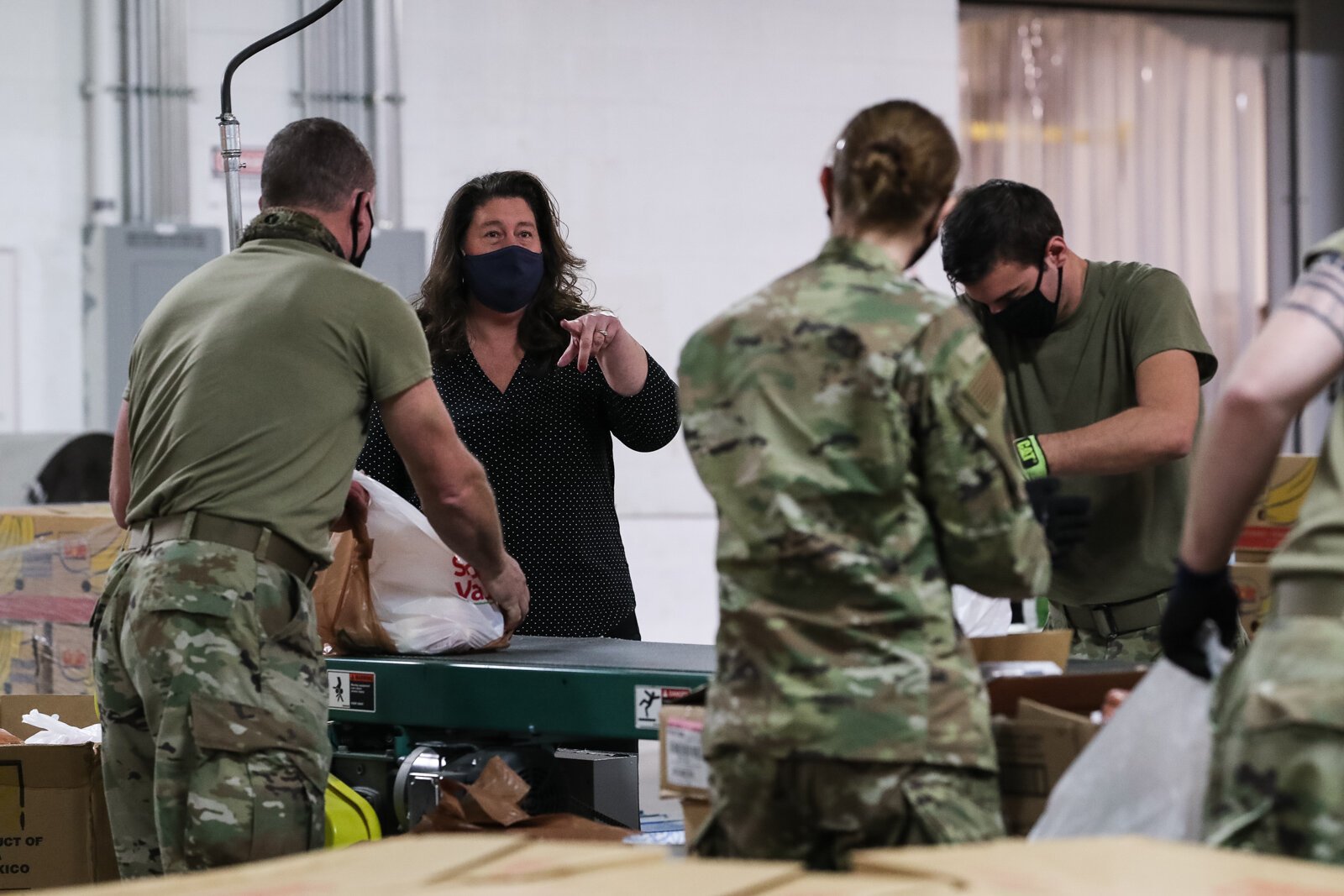 Kara Ross (in black) talks to Air Force Reserve members working in the Food Bank of Eastern Michigan warehouse.