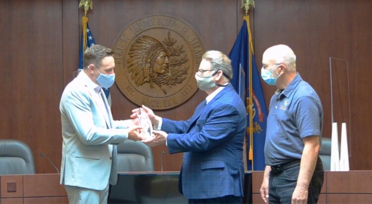 Greater Ottawa County United Way President Patrick Moran presents County Administrator Al Vanderberg and County Commission Chair Roger Bergman with the the G.W. Haworth Strength of the Community Award.