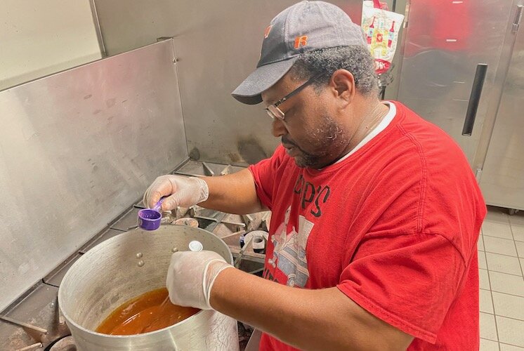John Capers adding ingredients to his sauce.