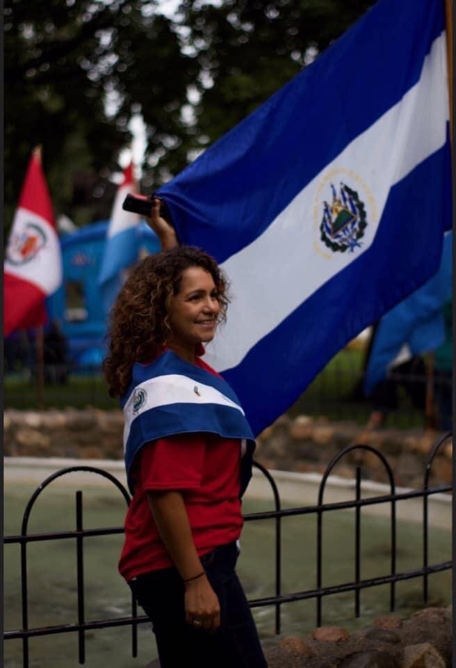 Fiesta co-chair Reyna Masko poses with the flag of her native El Salvador during the 2019 Fiesta,