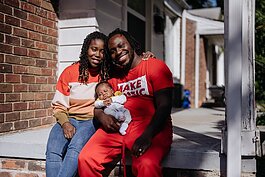 Darius Jones sits on the porch of his home with his fiancée and child.