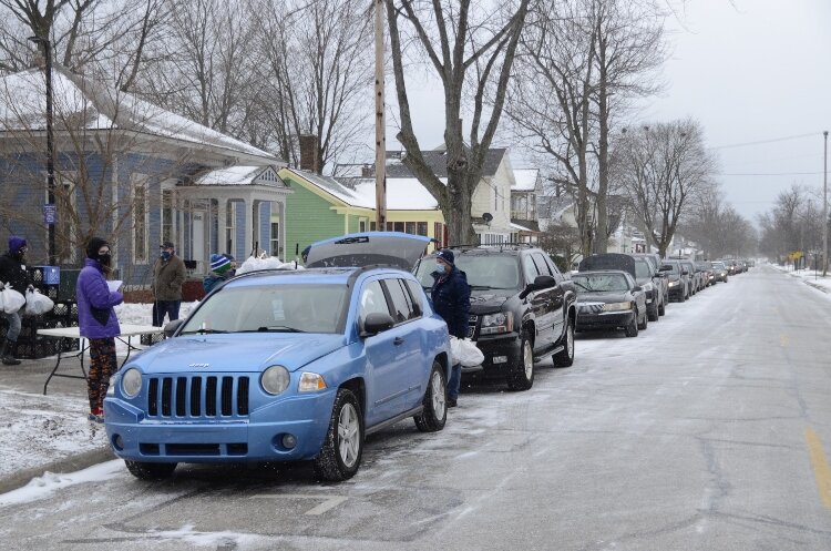 People line up in their cars for bags of food distributed by the Muskegon YMCA.