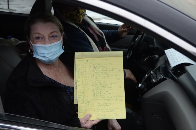 A resident pulls up to the Muskegon YMCA distribution site with a list of needed food items.