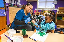 Teacher helping child at NEST Child Care and Parent Institute in Detroit