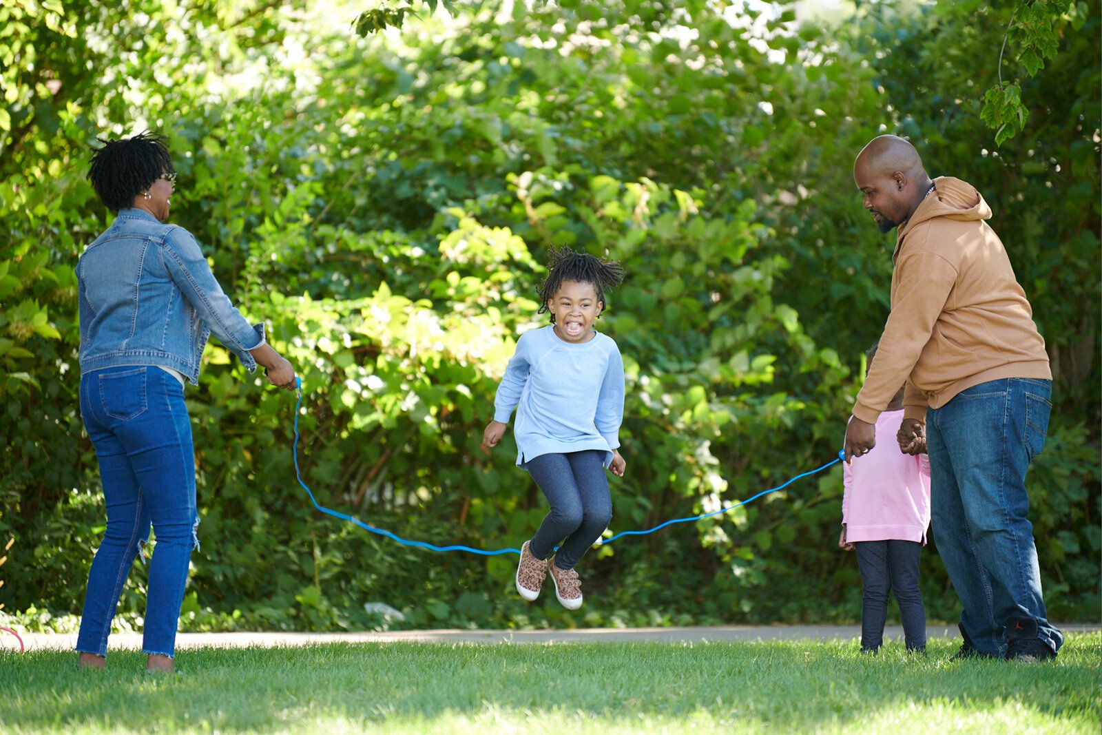 A family enjoys jump roping along the Lansing River Trail.